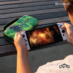 Person holding a Nintendo Switch with white Joy-Con controllers on a wooden bench, next to a green Hyperkin carrying case featuring Catworks artwork and branding.