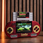 Hyperkin SupaBoy Portable in crimson lifestyle image with a SNES game cartridge on a wood surface