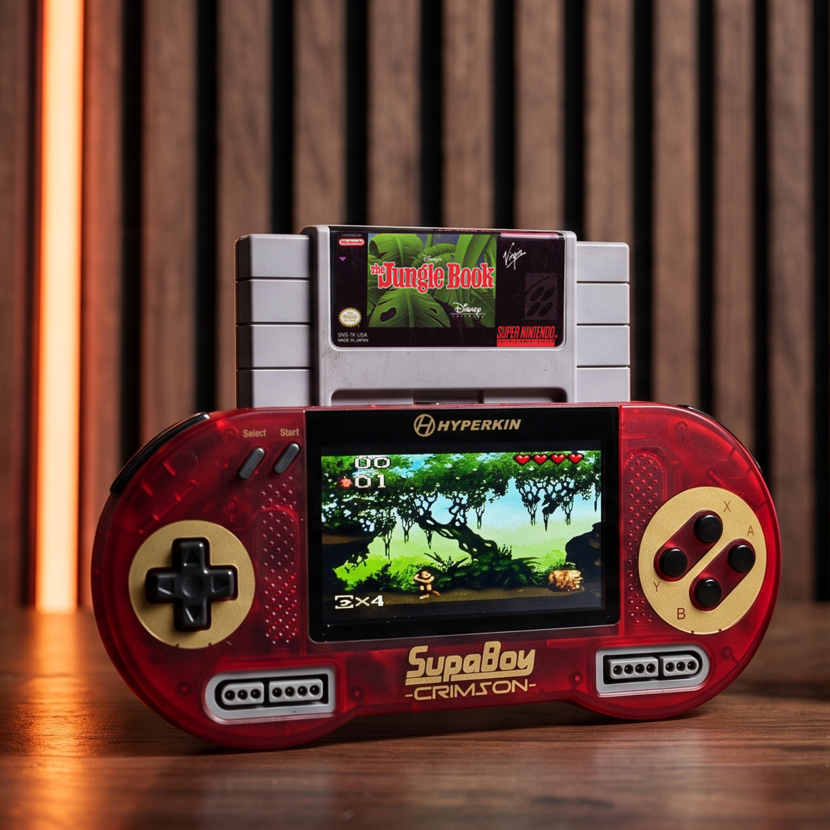 Hyperkin SupaBoy Portable in crimson lifestyle image with a SNES game cartridge on a wood surface