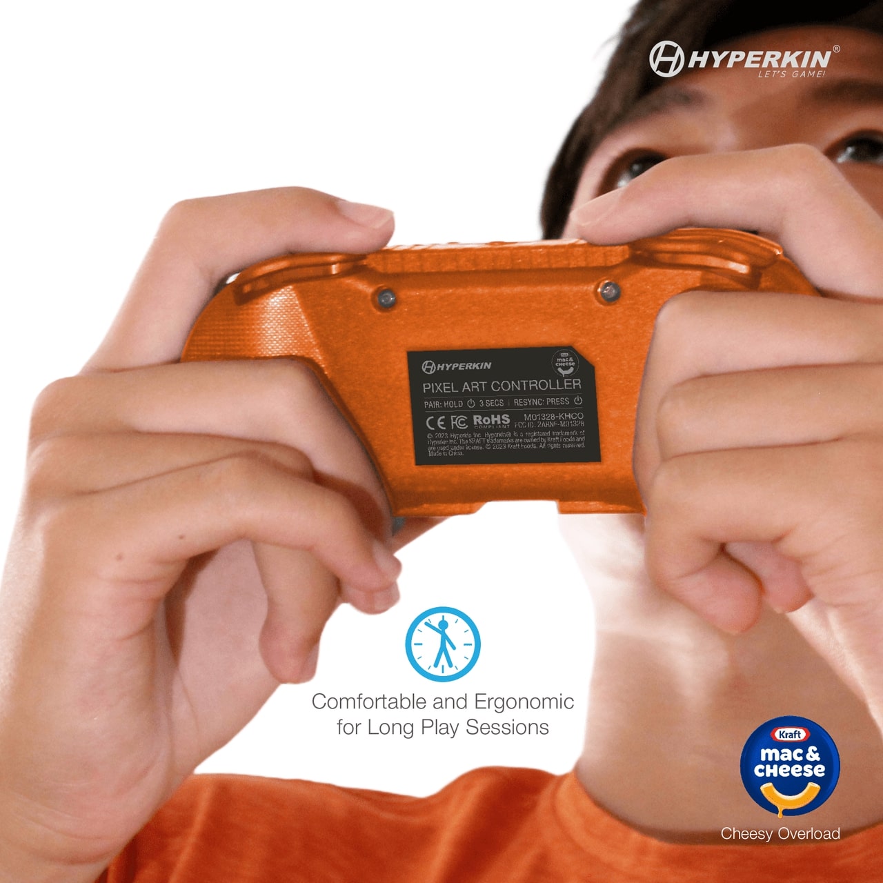 Person holding orange Hyperkin Pixel Art Controller, back view showing model details and certifications, with Kraft Mac & Cheese Cheesy Overload branding.