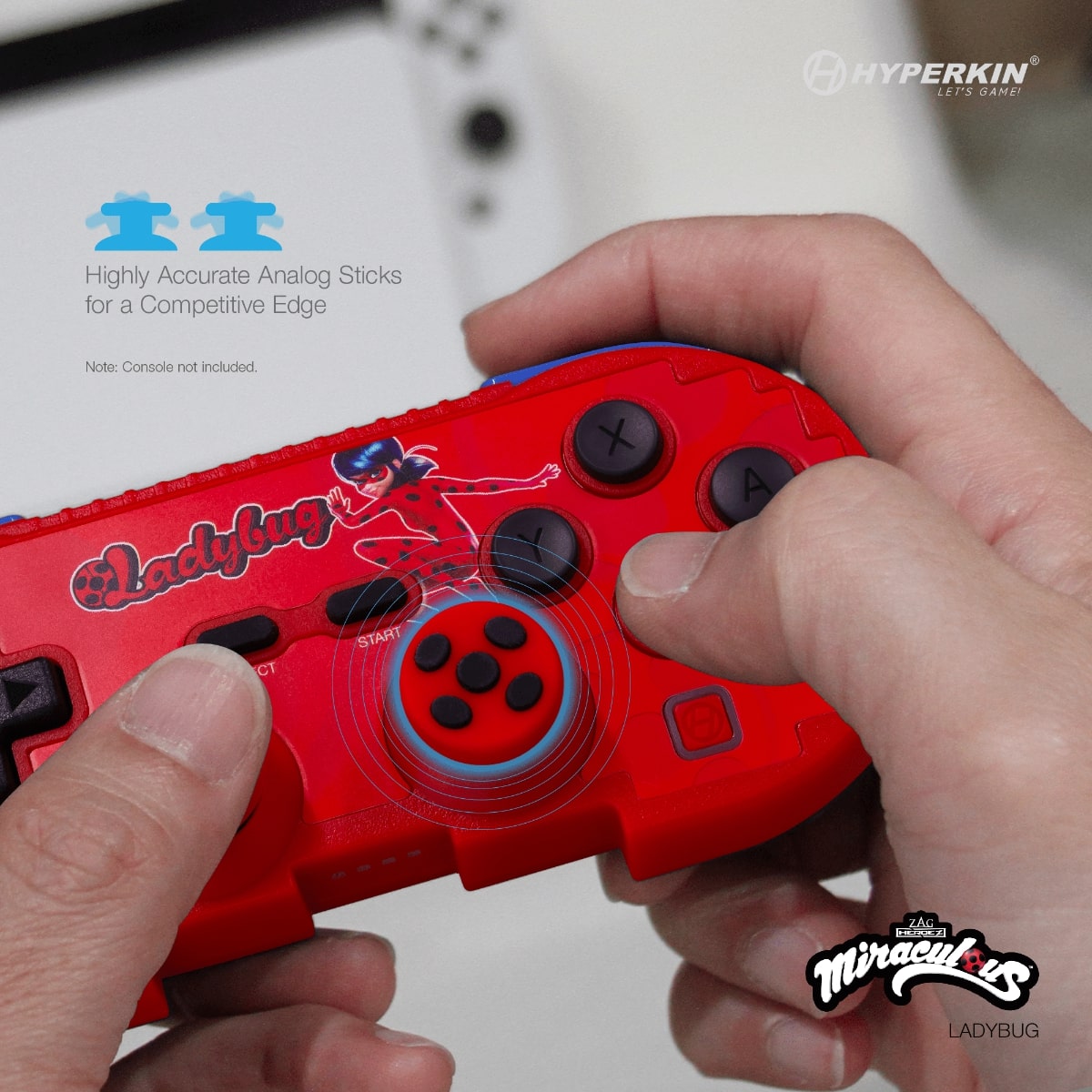 Person holding red Hyperkin gaming controller featuring Miraculous Ladybug character design, black buttons and analog sticks, and 'Ladybug' label; white console in background with text highlighting competitive analog stick accuracy; Hyperkin and Miraculous branding included.
