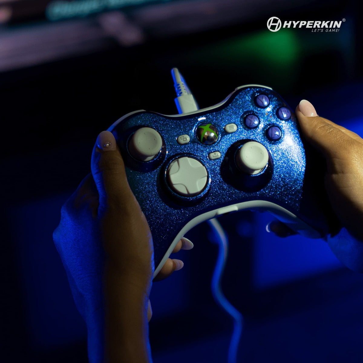 Blue gaming controller held by hands with Hyperkin logo in the corner