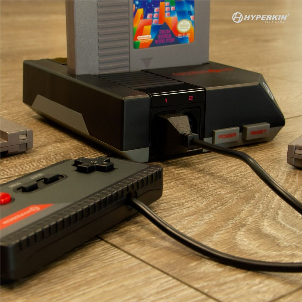 Retro gaming setup with Hyperkin RetroN 1 HD console, inserted cartridge, wired controller in port 1, POWER and RESET buttons visible; background features additional game cartridges and Hyperkin logo.